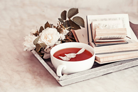 带书和玫瑰的新鲜茶杯特写