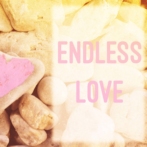 粉红色的心涂上口红在石头上，背景是许多小石头，上面写着文字，信，无尽的爱