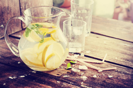 木桌上放柠檬水的壶和玻璃杯