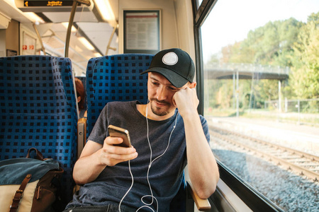 一个年轻人在火车上旅行时听音乐或播客。