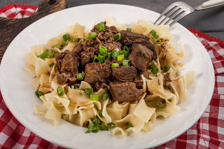 炖牛肉与塔利亚特尔意大利面在盘子里。