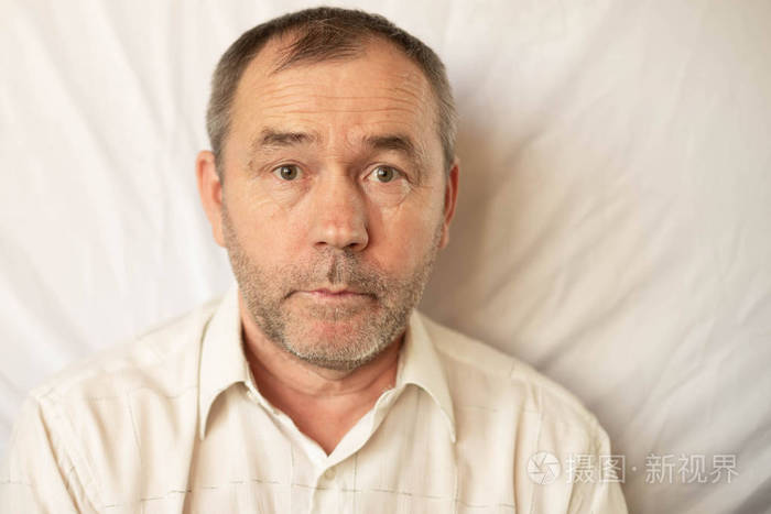 一名身穿白色衬衫未剃光头的男子在白色背景下近距离拍摄的肖像