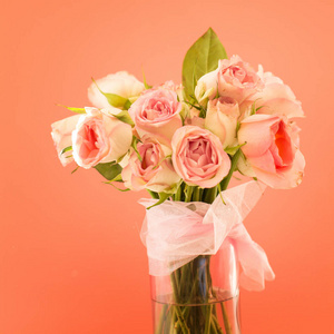 粉红色背景的花瓶里放着鲜嫩的玫瑰花