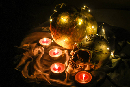 地狱万圣节头骨和南瓜在黑暗中与花环。温暖的光和棕色的蜡烛。
