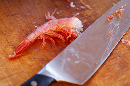 纯煮的虾和一把菜刀躺在砧板上