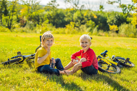 两个小男孩骑着自行车在公园里坐在草地上喝水