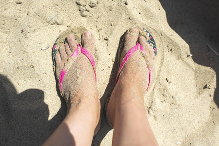 女人的脚在沙子上有拖鞋。 晴天