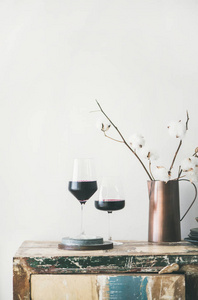 两杯红酒和鲜花在乡村厨房台面白色背景后面
