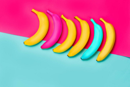 彩色和黄色的香蕉在彩色的蓝色和粉红色的背景上俯视照片