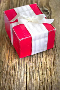 木质背景的红色丝带包裹圣诞礼物的特写镜头