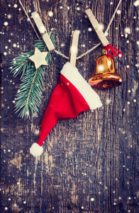 圣诞老人帽子和圣诞装饰品的特写镜头，老式风格挂在绳子上的木制背景上