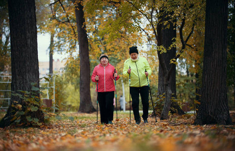 在北欧漫步的秋季公园里, 穿彩色夹克的成熟女性。广角镜头
