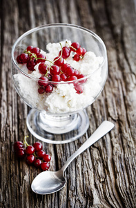 放在玻璃碗里的白色冰淇淋和红色浆果，放在木桌上