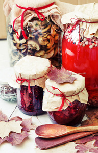 木桌上的季节性浆果果酱和罐装蘑菇