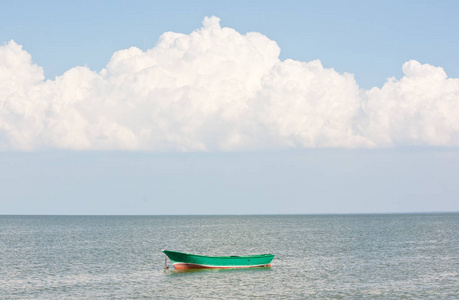 美丽的白云覆在海面上。 海上的绿色木船