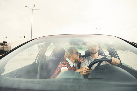 快乐的休闲夫妇在开车时交谈。 通过挡风玻璃的正面视图