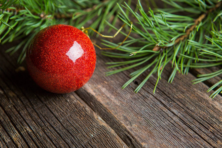 圣诞贺卡框架与地方为您的文字。 绿色冷杉树枝装饰红色玻璃圣诞球背景棕色旧木板