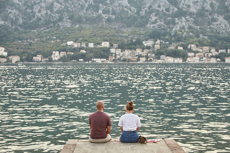 几个年轻人坐在 Kotor 的码头上。黑山