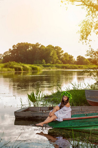 头上有花花环的年轻女子, 日落时在河上放松。女性美的概念, 在村里休息