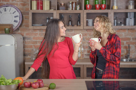 两个女孩在厨房里和一杯咖啡聊天