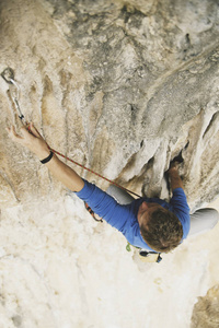 年轻人在悬崖上攀登富有挑战性的路线时抬起头来。