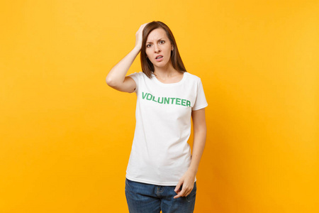 悲伤的肖像，心烦意乱，震惊的年轻女子穿着白色T恤，写着绿色标题，志愿者孤立在黄色背景上。 自愿无偿援助慈善恩典工作概念