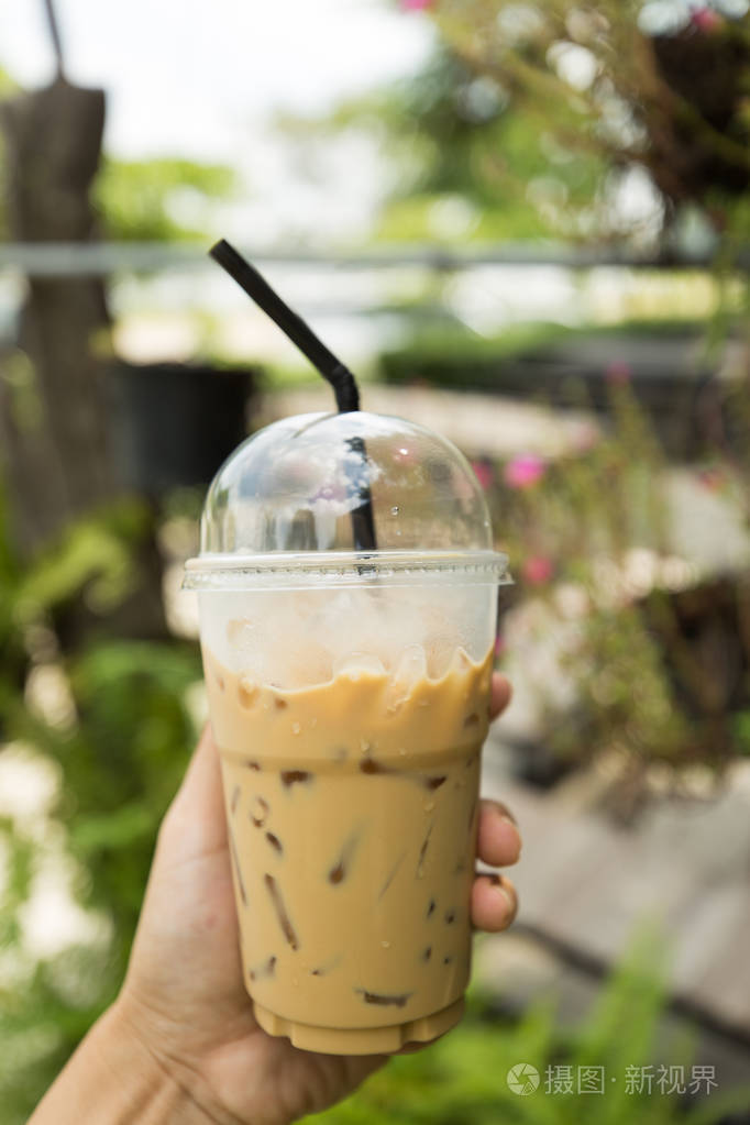 手拿浓缩咖啡冰咖啡,背景模糊.