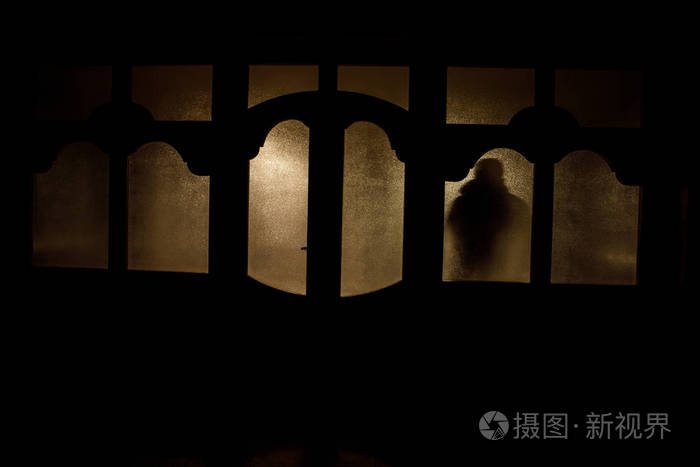 一个不知名的影子通过一扇紧闭的玻璃门在门上的剪影.