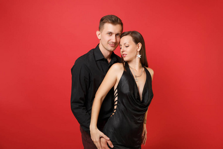 时尚的年轻夫妇穿着黑色的衣服，穿着衬衫，庆祝生日，节日聚会被隔离在明亮的红色背景上。圣瓦伦丁国际妇女节2019年新年快乐理念。准