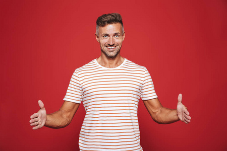 成功的男人30岁的条纹T恤，手势和演示大小与共空间隔离在红色背景上