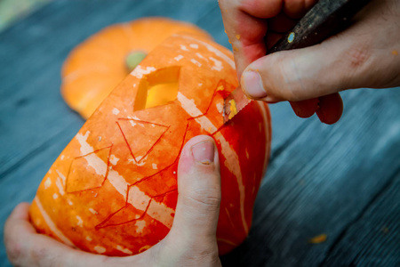 s hands with a knife make holes in the pumpkin.