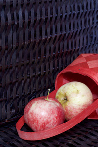 成熟的芳香苹果放在红色柳条篮子里。 在柳条篮子的背景下。