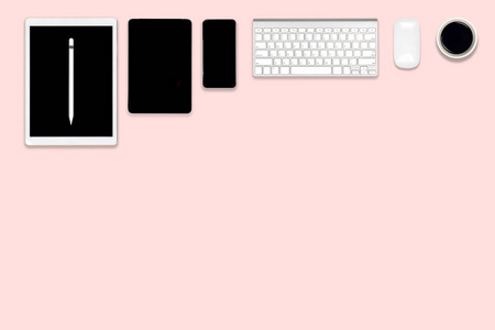 办公桌平面照片与数字平板手机和配件。 现代粉红色色调背景。 桌面办公室模型概念。