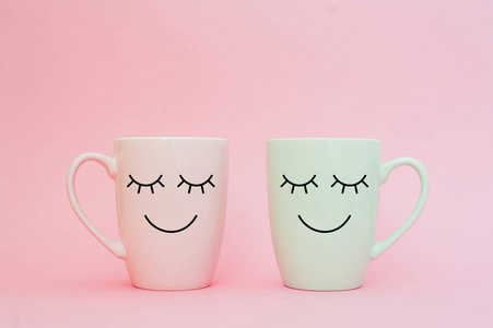 星期五快乐的词。两杯咖啡站在一起, 在粉红色的背景上的心形状与微笑的脸上的杯子。关于爱和关系的概念。创意彩卡贺卡