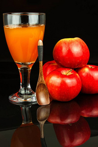 玻璃杯里的新鲜苹果汁。 水果收获。 健康饮料。 厨房桌子上的苹果。 生产果汁。 在黑色背景上
