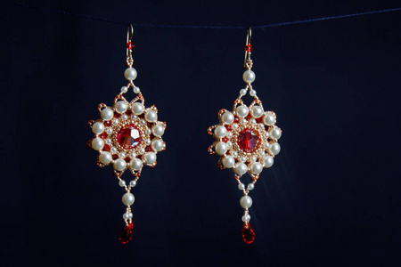 手工珠宝由珠子制成的宏。 白色珠子上的耳环。 石头上的耳环。 漂亮的装饰品。 红色珠子上的耳环。 黑色背景上的装饰品