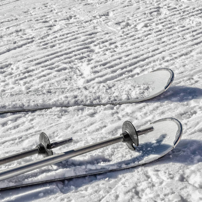 一对白色滑雪板在雪下部分可见一组金属滑雪杆留在新鲜的showcat机器