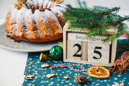 传统的圣诞水果蛋糕装饰粉状糖和坚果葡萄干旁边的木制日历与日期12月25日熟食自制糕点。 新年和圣诞节庆祝概念