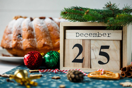 传统的圣诞水果蛋糕装饰粉状糖和坚果葡萄干旁边的木制日历与日期12月25日熟食自制糕点。 新年和圣诞节庆祝概念