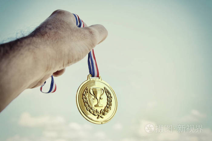 男子举起手拿金牌对抗天空奖励和胜利概念