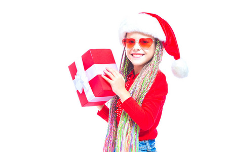 小女孩拿着圣诞礼物盒子的肖像，小女孩抱着她的礼物，在白色有趣的表情拥抱她的礼物。假日礼物。