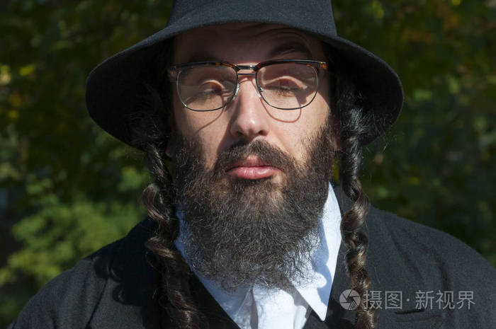 室外阳光明媚的肖像困惑的闭眼年轻的传统正统犹太男子黑胡子和戴眼镜