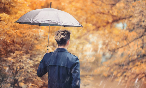 秋天下雨的天气和一个年轻的人用雨伞