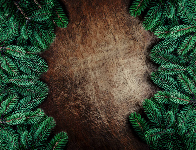 木制背景上有冷杉树枝的圣诞框架。