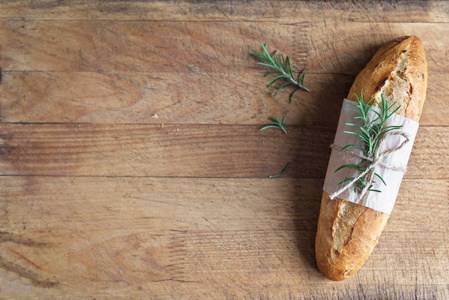 新鲜自制面包与迷迭香在乡村木制背景顶部视图复制空间。 酸面迷你面包。
