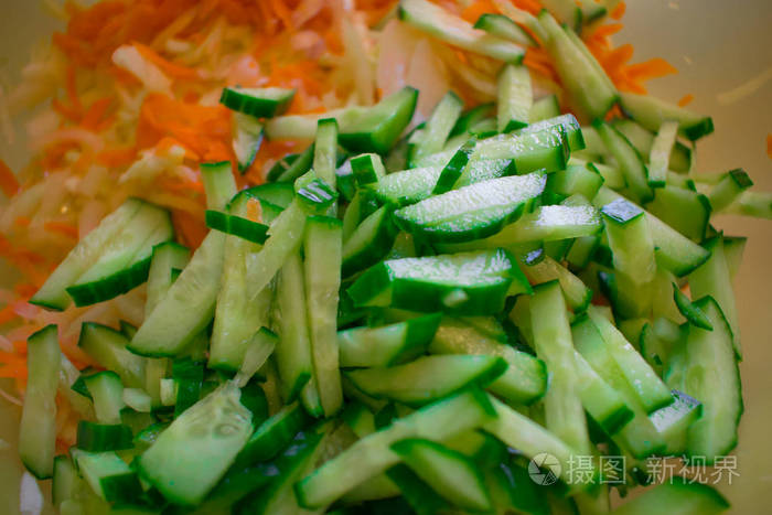 新鲜切片沙拉，从绿色成熟黄瓜和胡萝卜与卷心菜吸管