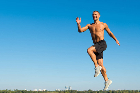 男子运动员肌肉躯干运行。晨跑充满了活力。动机和成就。晨跑习惯。赛跑者运动向前天空背景。迈向成功。健康生活的日常训练