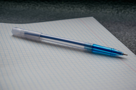 蓝色的钢笔和白色的笔记本，放在笼子里，黑色的背景上，关闭