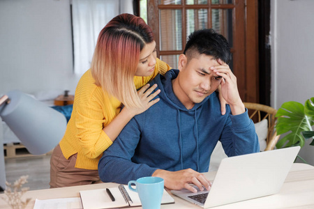 亚洲女性女朋友鼓励男友从压力，同时在家里的笔记本电脑上工作