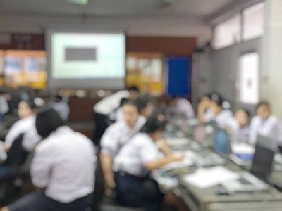 教育概念抽象模糊背景图像的学生和商务人员学习和讨论在大大厅行业研讨会与屏幕和投影仪显示信息。